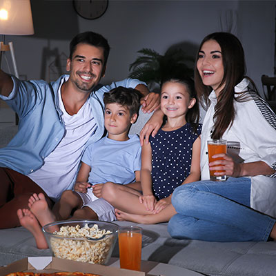 family relaxing in smart home watching the tv on the sofa at night.